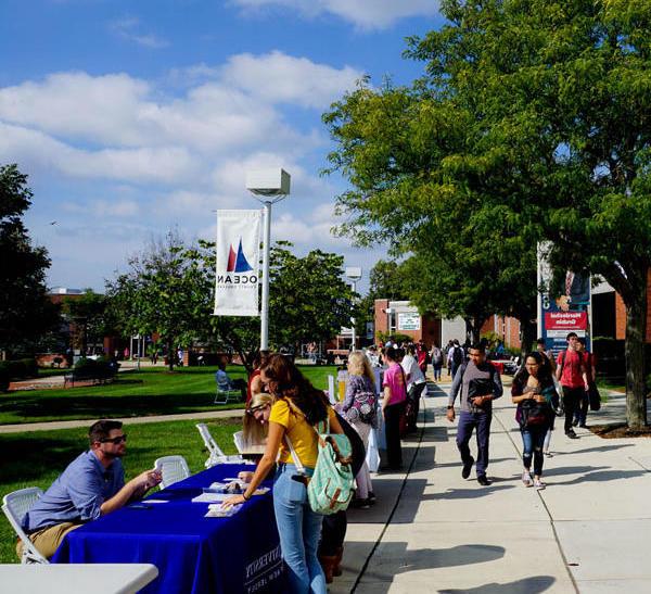 Students on campus at an event talking to different booths